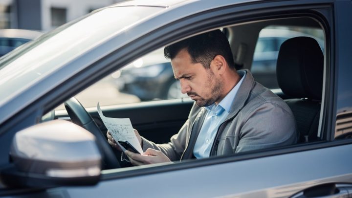 Conducteur examinant ses documents d'assurance auto dans sa voiture